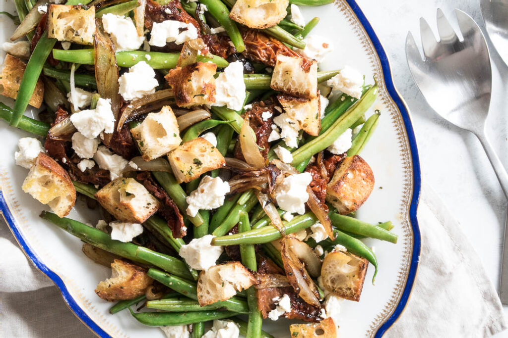 Bønnesalat med tomat, karamelliserede løg, feta og croutoner - opskrift på fransk salat med bønner